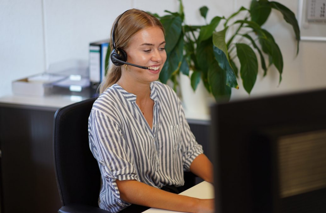 Frau mit Headset vor Computer